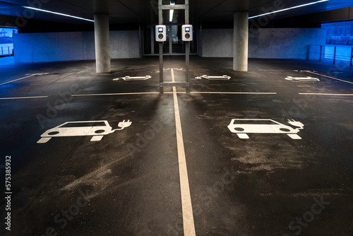 Blick auf mehrere leere Parkplätze mit Ladestationen für Elektroautos, blau weiße Beleuchtung, horizontal  photo