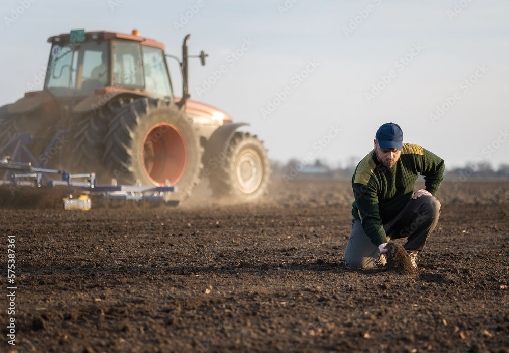 Farmer examing dirt while tractor is plowing field Farmer examing dirt while tractor is plowing field