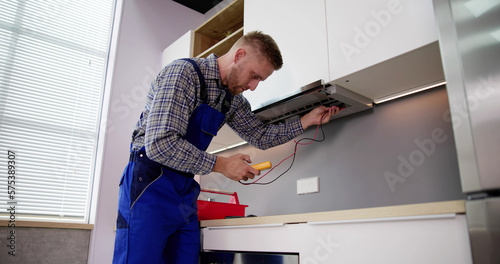 Male Worker In Overall Testing Kitchen Hood With Multimeter