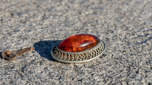 Orange old Baltic amber brooch in silver on a gray stone. 
Natural amber jewelry. photo