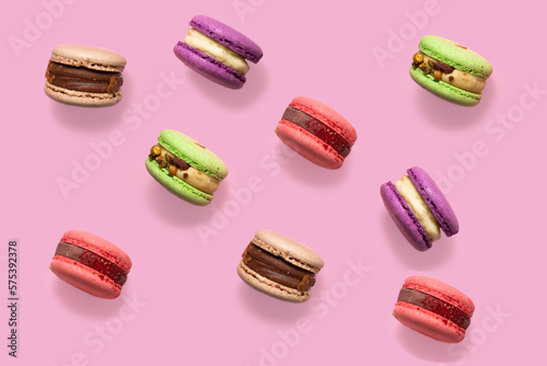 Sweet colorful macarons isolated on pink background. Tasty red, green, brown, violet macaroons.