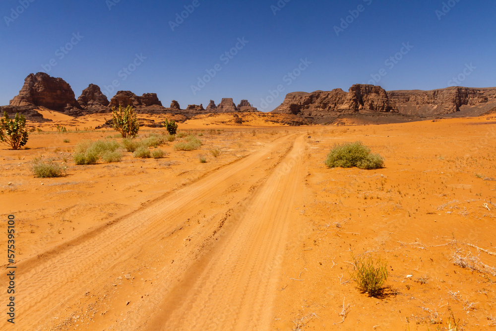 Empty sandy dirt road with tire tracks in Tassili National Park. Tadrart mountains, Acacus range. Tassili N'Ajjer National Park. Algeria, Africa  