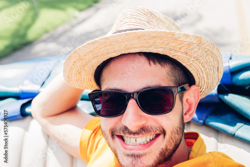 Photography Positive male tourist in straw hat and sunglasses smiling while looking at camera during road trip in cabriolet in Cuba