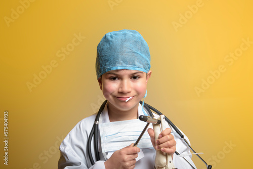 Adorable future doctor 7 years old boy isolated on yellow. photo