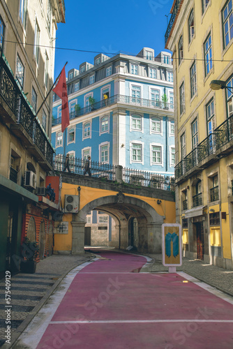 Fototapeta Naklejka Na Ścianę i Meble -  Narrow street with pink road and bridge in Lisbon, Portugal