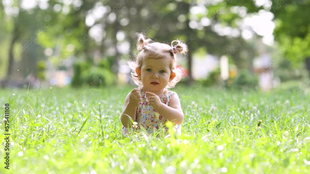 cute little girl in cotton clothes is sitting on the green grass in the park. cute little girl in cotton clothes is sitting on the green grass in the park.