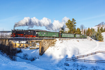 Fichtelbergbahn steam train locomotive railway on a bridge in winter in Sehmatal, Germany