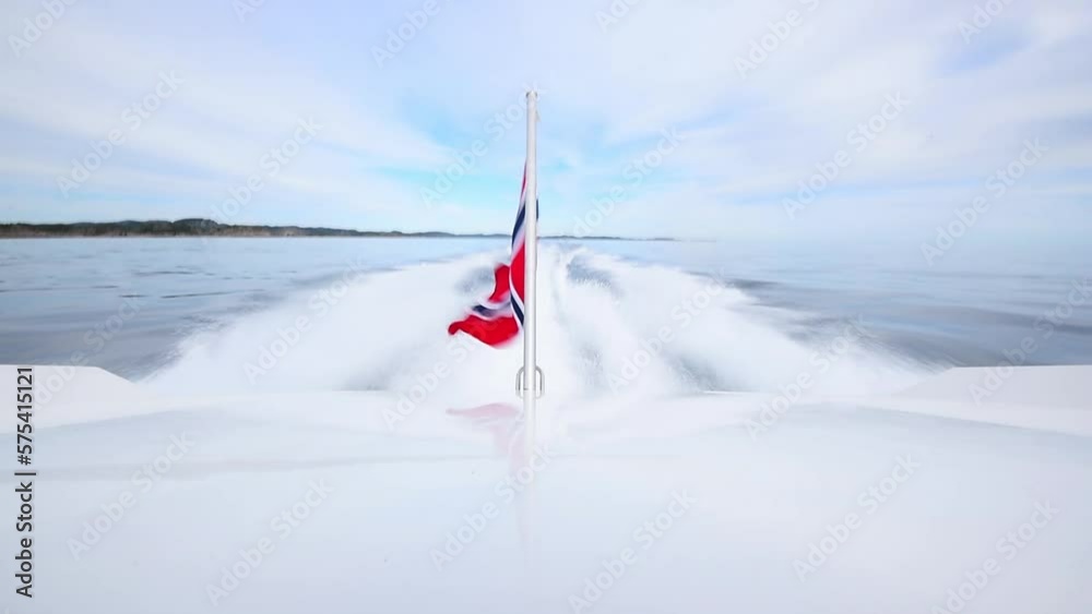 Powerboat at high speed over open sea having a norwegian flag at the stern.