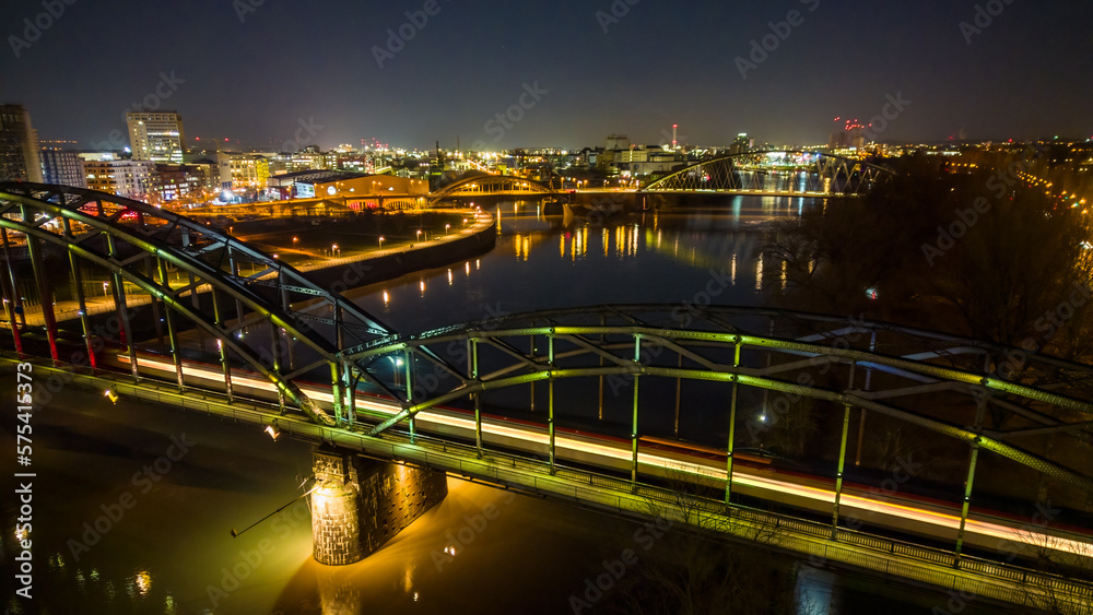 Light trail of a train on the bridge over the river in the city at night