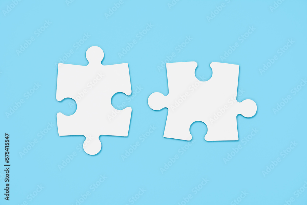 Two empty white matching puzzle pieces on blue background Two empty white matching puzzle pieces on blue background