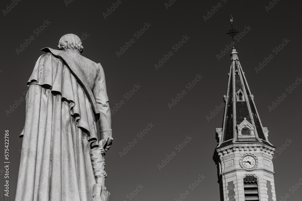 Naklejka premium Gap, Hautes Alpes, France : Statue of the Baron Ladoucette (19th century) and the tower of the Eglise des Cordeliers (Church of the Cordeliers).