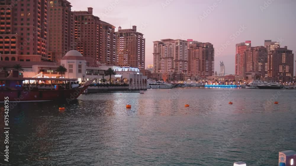 Porto Arabia Marina in The pearl Doha, Qatar daylight summer shot showing luxurious yachts and boats docked at the marina with residential buildings in background. Porto Arabia Marina in The pearl Doha, Qatar daylight summer shot showing luxurious yachts and boats docked at the marina with residential buildings in background.
