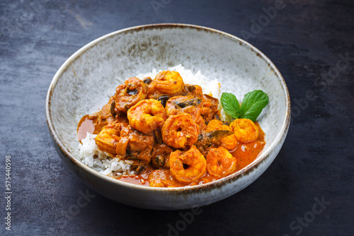 Traditional spicy Indian prawn Madras curry Rogan Josh with king prawns and basmati rice served as close-up in a Nordic design bowl with copy space photo