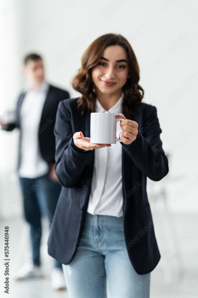 The team in the office. A woman with a white cup in her hands. Empty cup with space for text or logo. The team in the office. A woman with a white cup in her hands. Empty cup with space for text or logo.