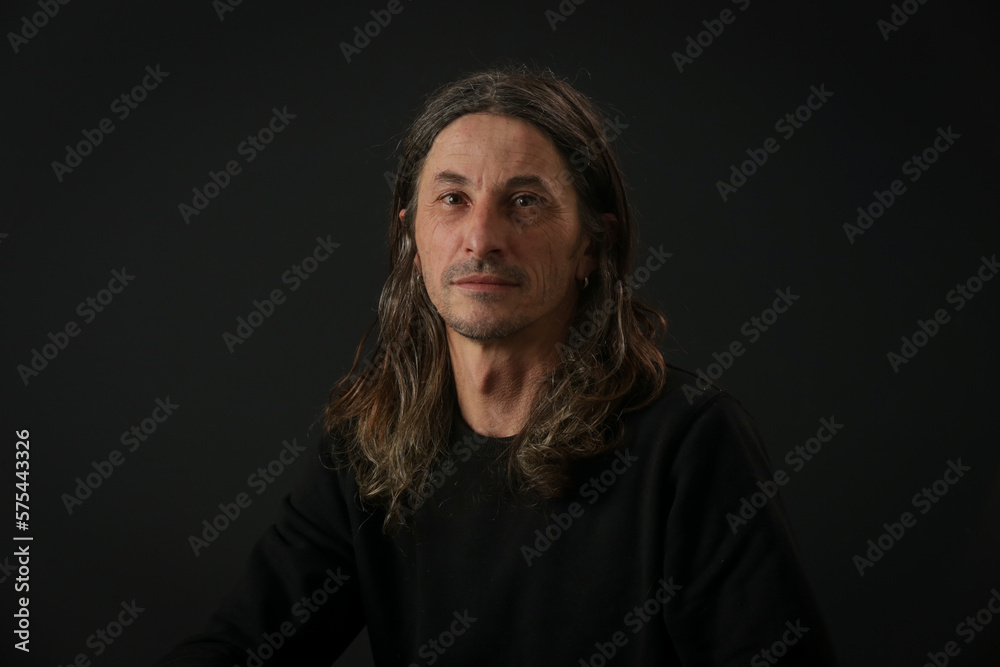 Portrait of middle aged man with long hair on black background