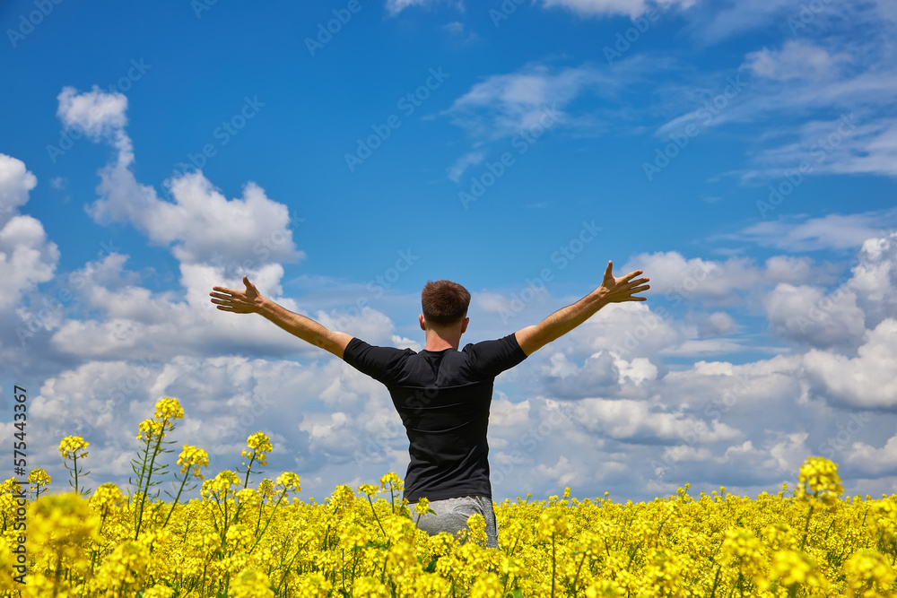 Man with arms outstretched. Handsome young man standing in a field of blooming yellow rapeseed flowers. Man with arms outstretched. Handsome young man standing in a field of blooming yellow rapeseed flowers.