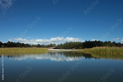 Vista de un rancho reflejado en el lago con un bosque al fondo