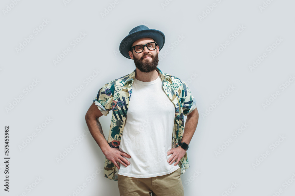 Young bearded hipster wearing Hawaiian shirt, hat and white blank t-shirt with copy space for text or logo. Layout for design Young bearded hipster wearing Hawaiian shirt, hat and white blank t-shirt with copy space for text or logo. Layout for design