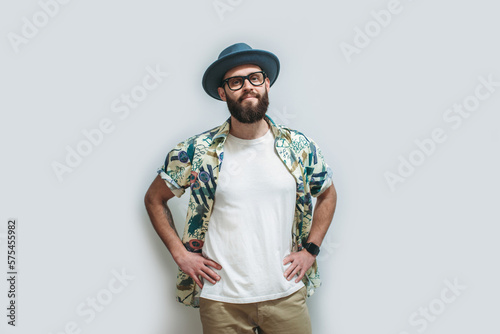 Young bearded hipster wearing Hawaiian shirt, hat and white blank t-shirt with copy space for text or logo. Layout for design