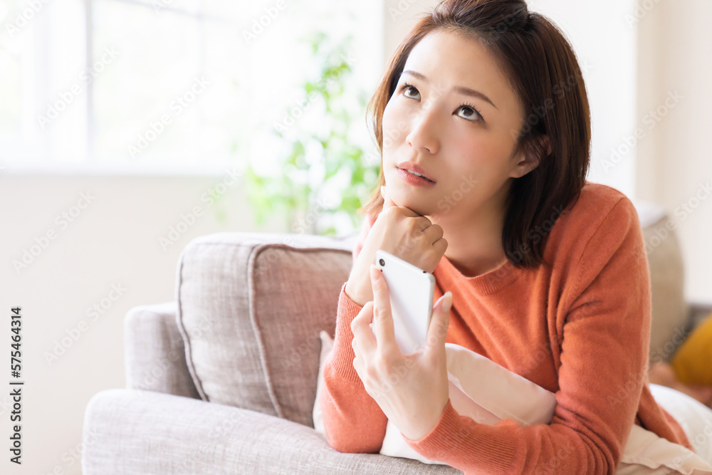 部屋でスマホを見る女性 考える 部屋でスマホを見る女性 考える