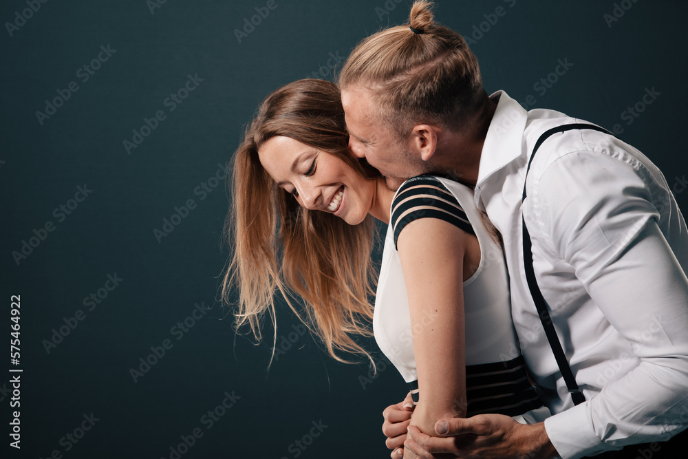 Fototapeta premium young sensual couple is lost in their own world of love and desire. Their bodies entwined as they share an intimate moment when he kiss her neck and she smiles
