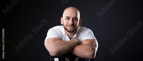 Photos turkish student man with bald head and white polo shirt lean on chair back with