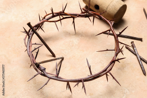 Crown of thorns with nails and mallet on beige background  closeup. Good Friday concept