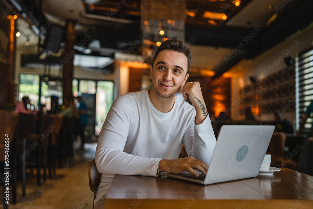 One man young adult caucasian male working on laptop computer at cafe