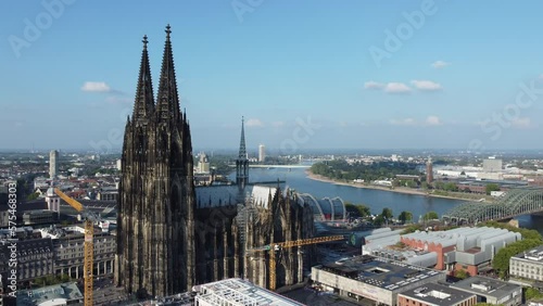 german cologne cathedral shot from above by drone fly around the building with construction crane in front and rhine river and landskape of city in the background on sunny summer day photo