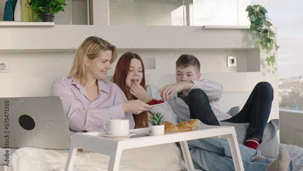 Mother having breakfast in bed with her childrens at mothers day. family breakfast in bedroom. Happy mother with her little daughter and son having breakfast together in bed at home. Mother having breakfast in bed with her childrens at mothers day. family breakfast in bedroom. Happy mother with her little daughter and son having breakfast together in bed at home.