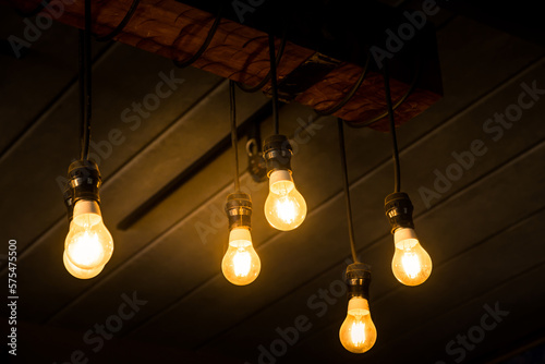 House interior of loft and rustic style. Beautiful vintage luxury light bulb hanging decor glowing in dark. Retro filter effect style. Blend of history and modern.