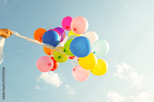 Hand holding multi colored balloons done with a retro vintage  filter effect. concept of festival, celebration, birthday, for background design.