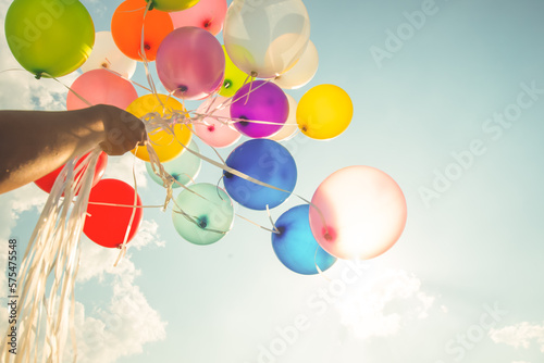Hand holding multi colored balloons done with a retro vintage  filter effect. concept of festival, celebration, birthday, for background design.