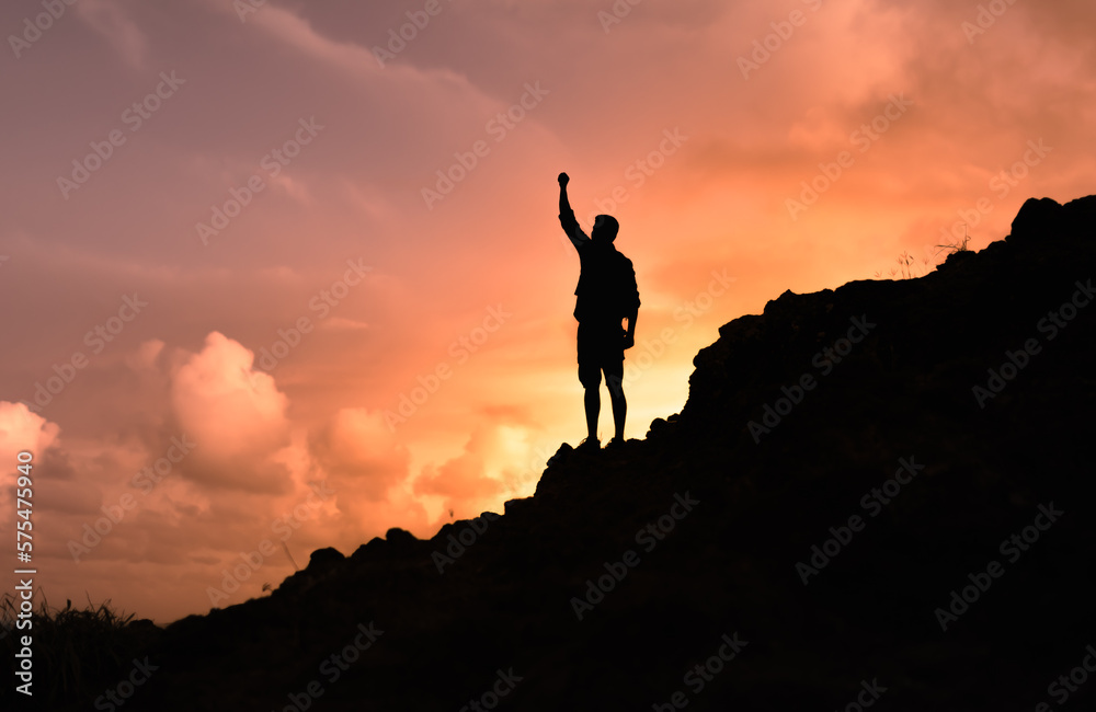 silhouette of a male hiker on a mountain top. People power, victory, and goal setting concept. 