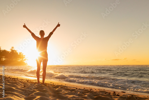 Young female feeling grateful joyful with thumbs up to the ocean sunrise 