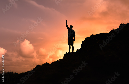 silhouette of a male hiker on a mountain top. People power, victory, and goal setting concept. 