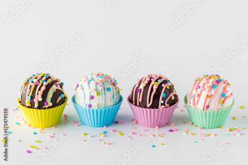 A row of hot cocoa bombs decorated with candy melts and sprinkles.