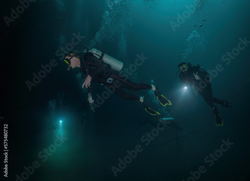 three divers using their flashlights in a cenote in mexico