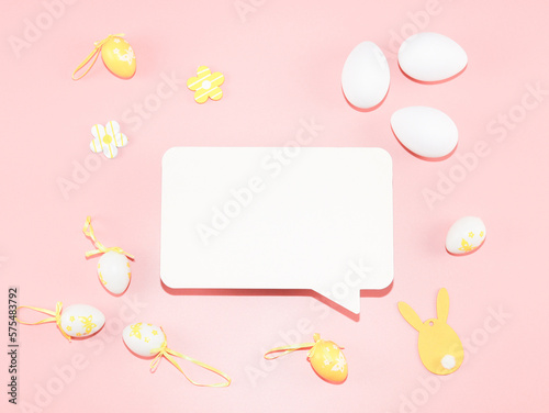 Empty white callout, decorative yellow-white eggs, and a wooden easter bunny on a light pink.