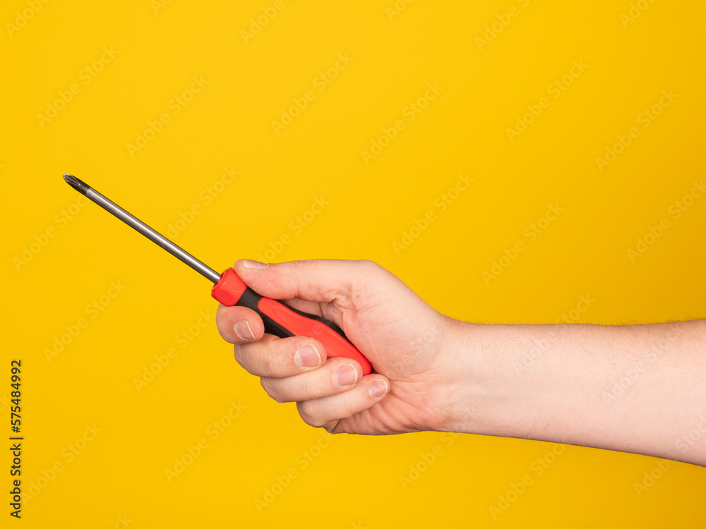 Hand holding a screwdriver. No face, yellow background.
Hand holding a screwdriver. No face, yellow background.
