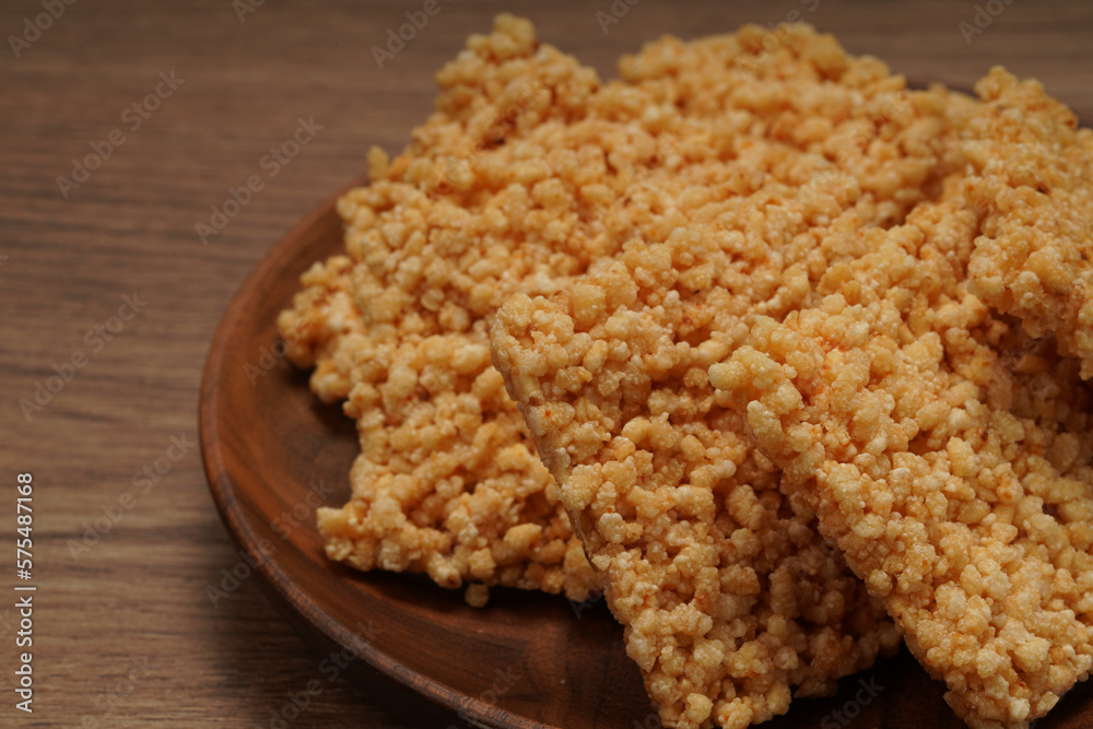 A plate of crispy rice is on the wooden table A plate of crispy rice is on the wooden table