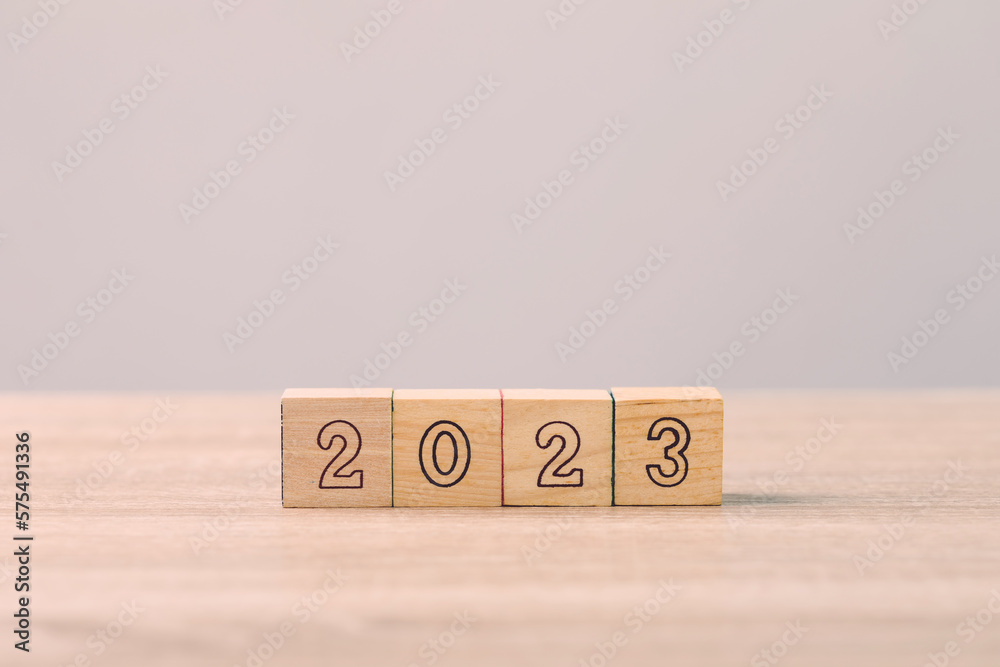 Businessman's hand is sorting out a wooden dice with the number of 2023 on the table. Work concept in 2023 Businessman's hand is sorting out a wooden dice with the number of 2023 on the table. Work concept in 2023