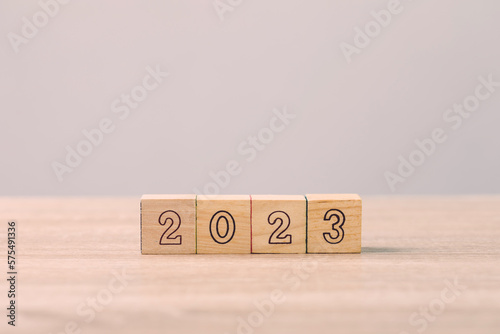 Businessman's hand is sorting out a wooden dice with the number of 2023 on the table. Work concept in 2023