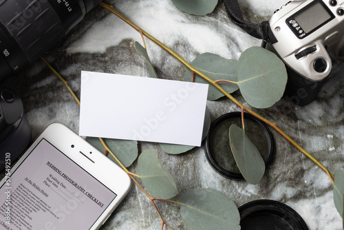 Blank, white business card mock-up for wedding photography business with cameras, eucalyptus, lenses, phone, wedding rings
