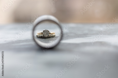 close up of women's diamond ring and diamond wedding band looking through man's wedding band