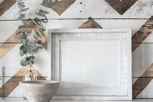 Blank, white picture frame mock-up farmhouse style with jar of eucalyptus and a decorative chevron wooden background