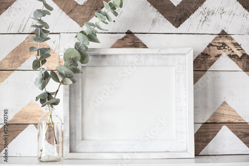 Blank, white picture frame mock-up farmhouse style with jar of eucalyptus and a decorative chevron wooden background