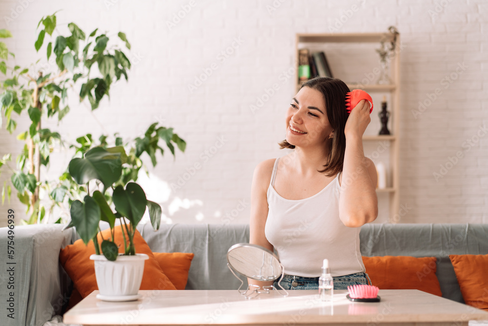 Woman sitting on couch gives herself head massage with scalp massager. Woman sitting on couch gives herself head massage with scalp massager.