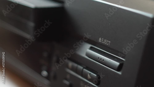 close-up finger presses the eject button and the video cassette is taken out of the video player. selective focus. video recording on a vintage video cassette.