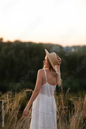 Young pretty woman in dress and hat outdoors posing in a field